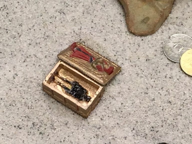 A small box with a black and red object on the ground